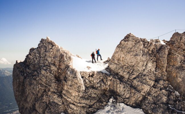 Zwei Menschen stehen auf dem Gipfel der Zugspitze