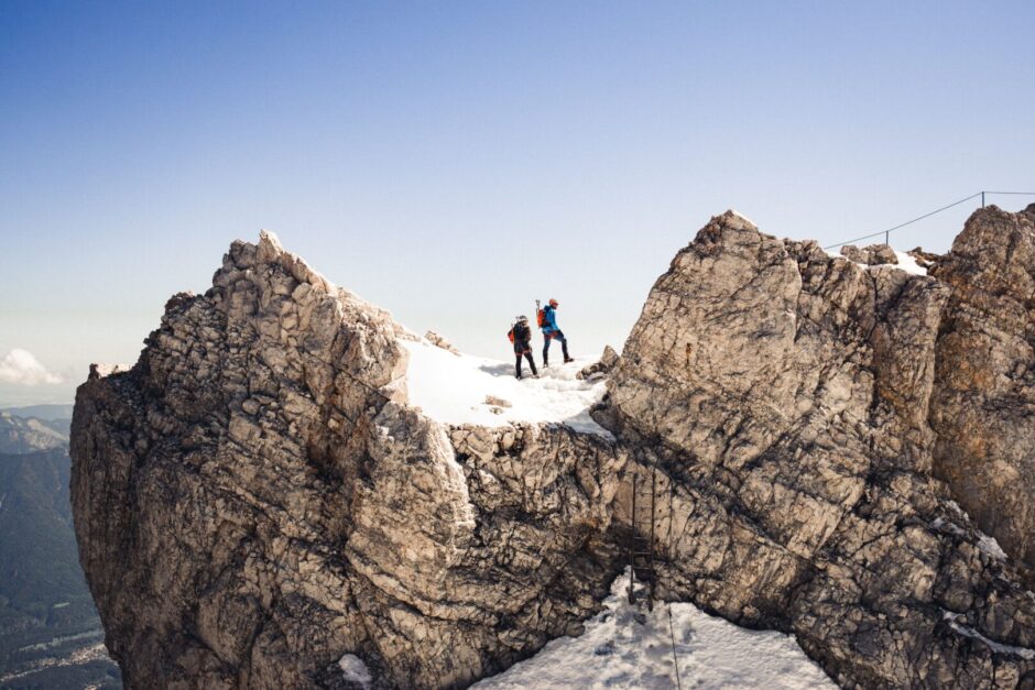 Zwei Menschen stehen auf dem Gipfel der Zugspitze