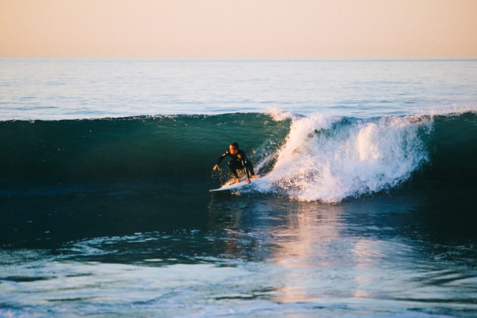 Ein Surfer auf einer Welle in der Abendsonne