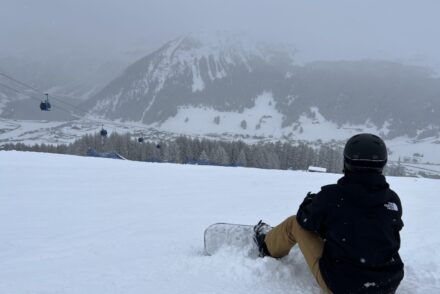 Ich sitze mit meinem snowboard oben auf dem Berg in Livigno bei schlechten Bedingungen