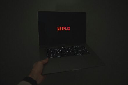 Laptop mit Netflix drauf im dunkeln von einer Hand gehalten